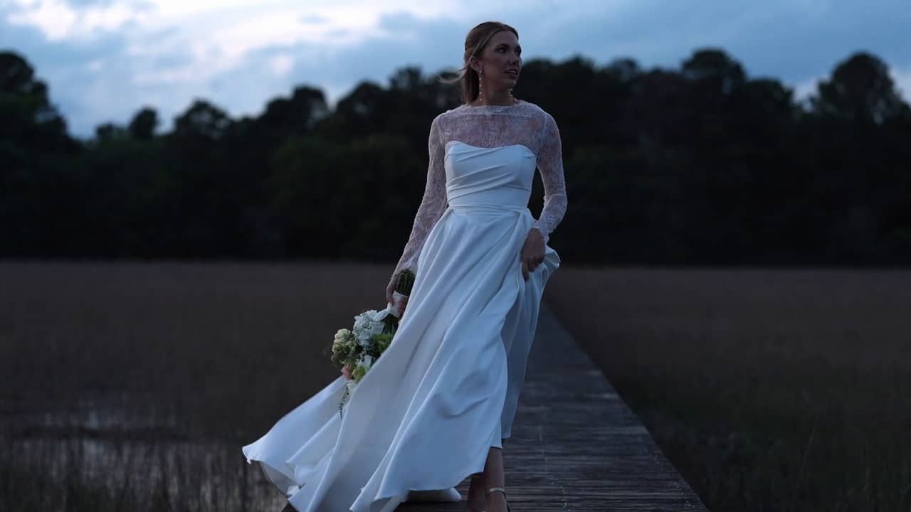 A bride walking a marsh boardwalk at dusk near Charleston, South Carolina